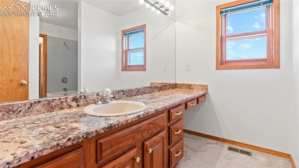 16250 Herring Road Colorado Springs, CO 80908 - Photo 32 of 50 a bathroom with a granite countertop sink and a mirror