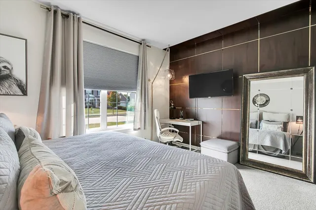 a bedroom with a bed a mirror and a flat tv screen on the dresser