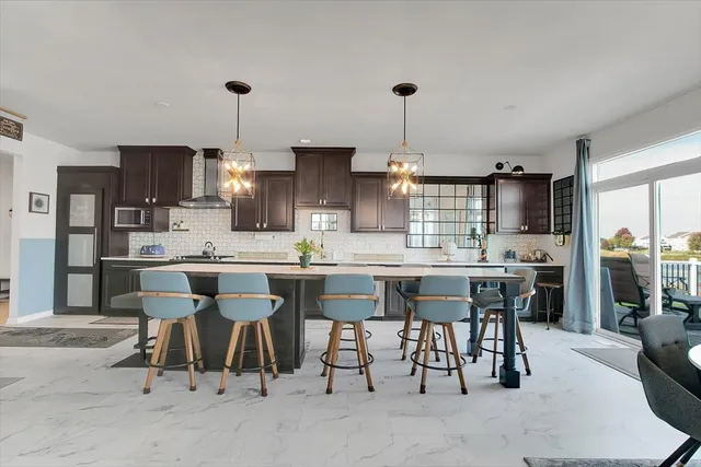 a kitchen with kitchen island granite countertop a table chairs sink and cabinets