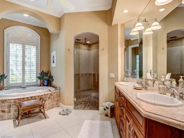 a spacious bathroom with a sink a mirror a bathtub and next to a window