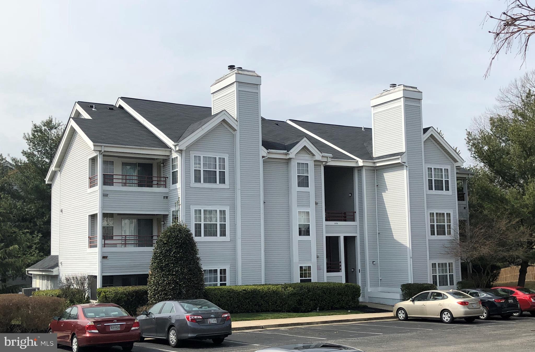 a front view of a building with cars parked