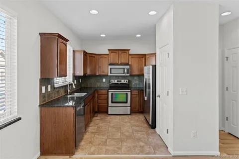a kitchen with stainless steel appliances granite countertop a refrigerator and a stove top oven