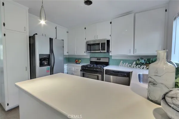 a kitchen with stainless steel appliances a stove a refrigerator a sink a stove with white cabinets