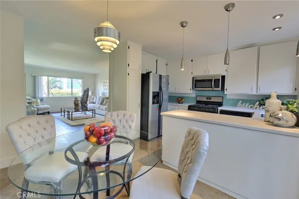 a kitchen with stainless steel appliances granite countertop a dining table chairs refrigerator and microwave