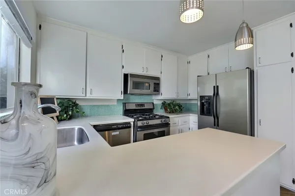 a kitchen with granite countertop a refrigerator sink and white cabinets