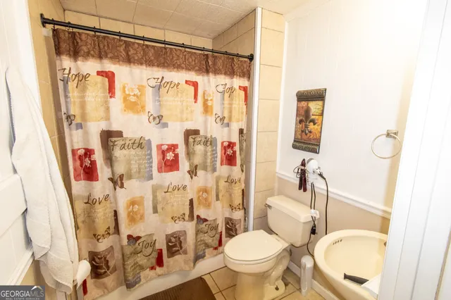 a bathroom with a shower curtain sink and a toilet