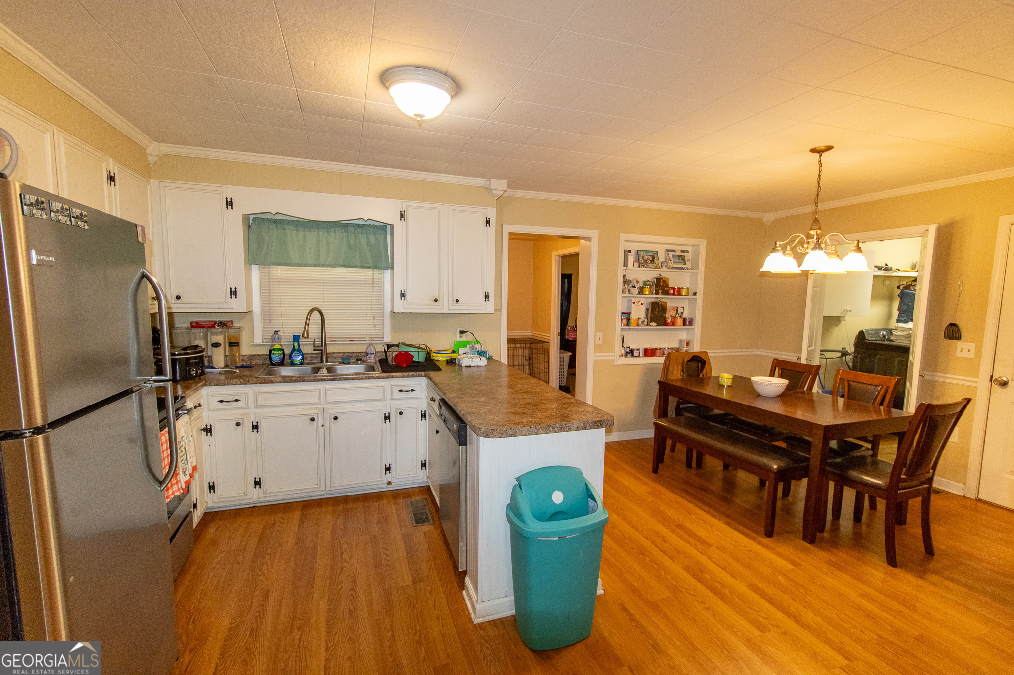 209 Elm Drive Brooklet, GA 30415 - Photo 8 of 30 a kitchen with stainless steel appliances a stove a sink a refrigerator a dining table and chairs with wooden floor