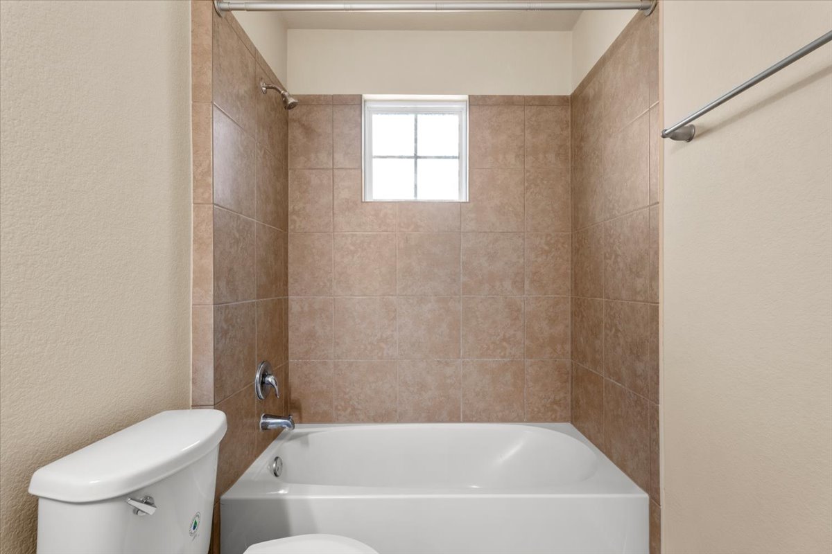 3451 Mayfield Ranch Boulevard, Unit 311 Round Rock, TX 78681 - Photo 34 of 40 Bathtub with tiled surround, chrome fixtures, and a privacy window