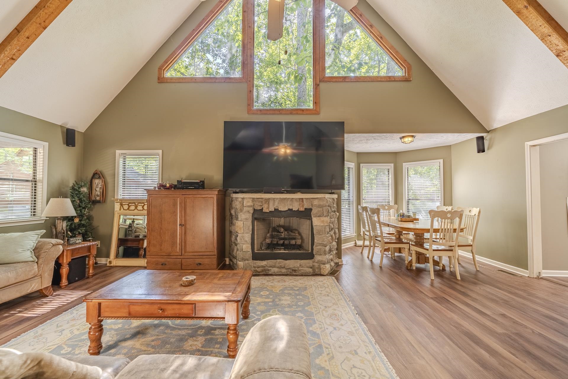 435 Murray Lane Counce, TN 38326 - Photo 8 of 34 Vaulted ceiling living area featuring a stone-faced fireplace, wood-finish flooring, exposed wood beams, and large triangular windows
