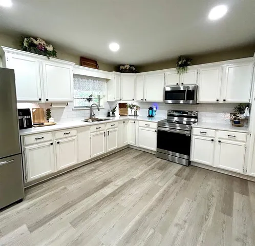 a kitchen with stainless steel appliances granite countertop a sink a stove a refrigerator cabinets and a microwave