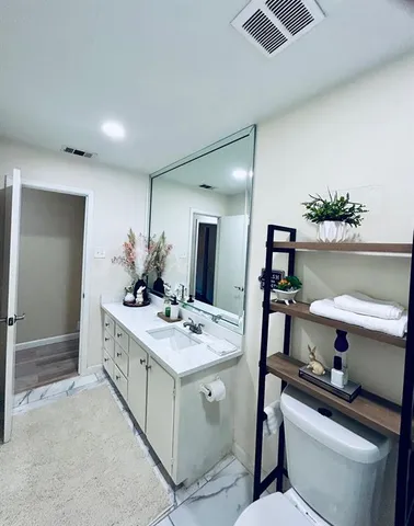 a bathroom with a sink vanity granite and toilet