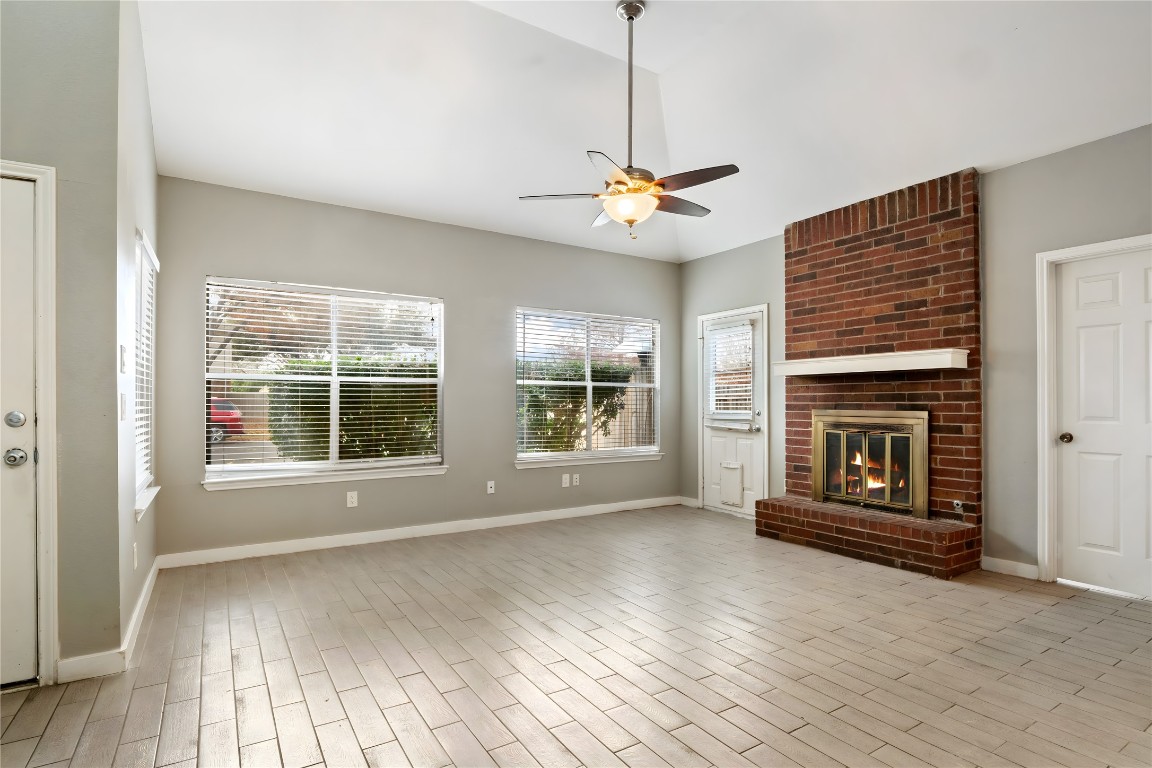 16801 Gravesend Road Pflugerville, TX 78660 - Photo 3 of 30 Living room with a fireplace, healthy amount of natural light, ceiling fan, vaulted ceiling, and wood finished floors