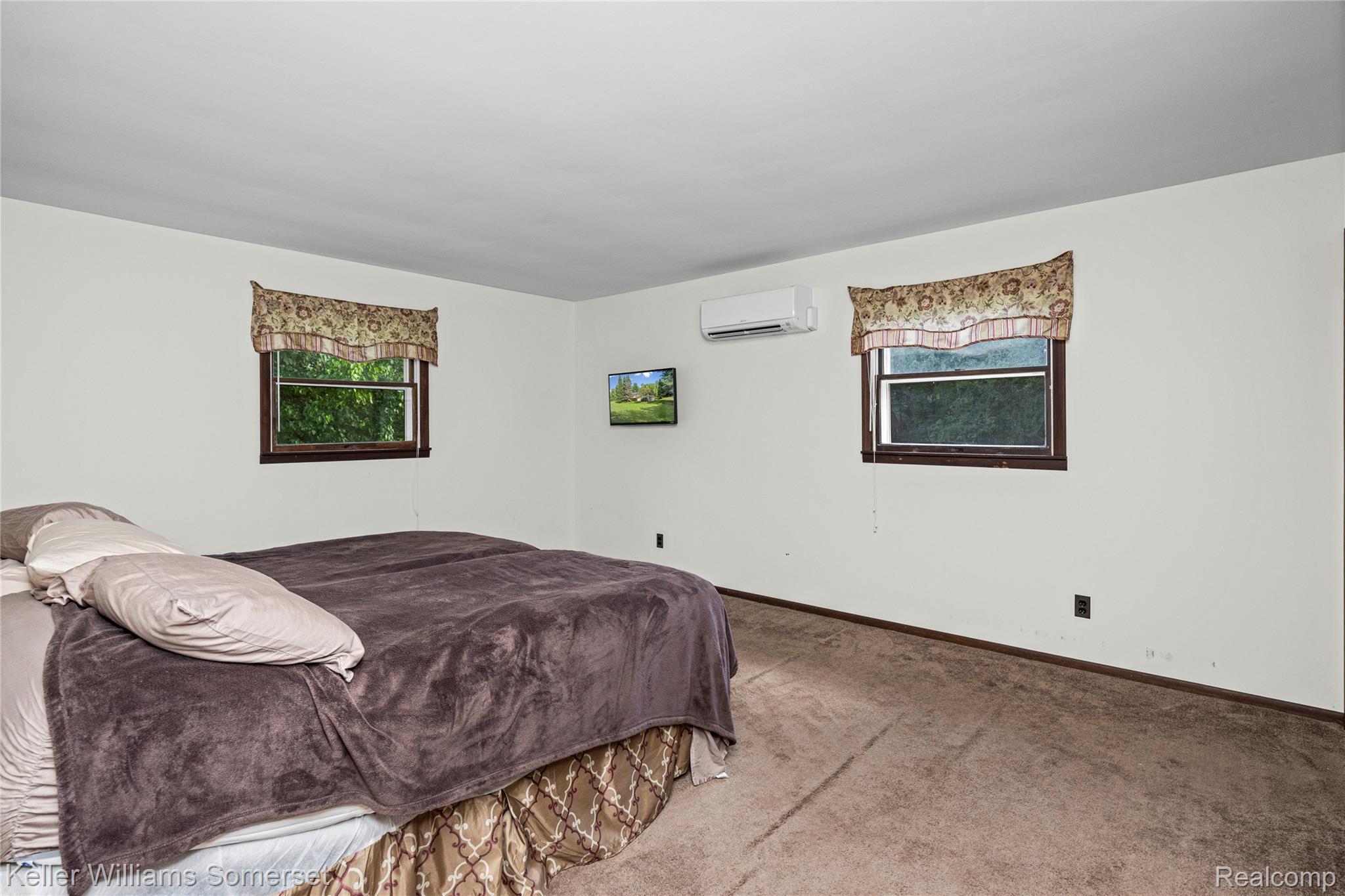 2344 Rochester Road Leonard, MI 48367 - Photo 24 of 66 Bedroom featuring two windows with valances, light-colored walls, carpeted flooring, and a wall-mounted mini-split system