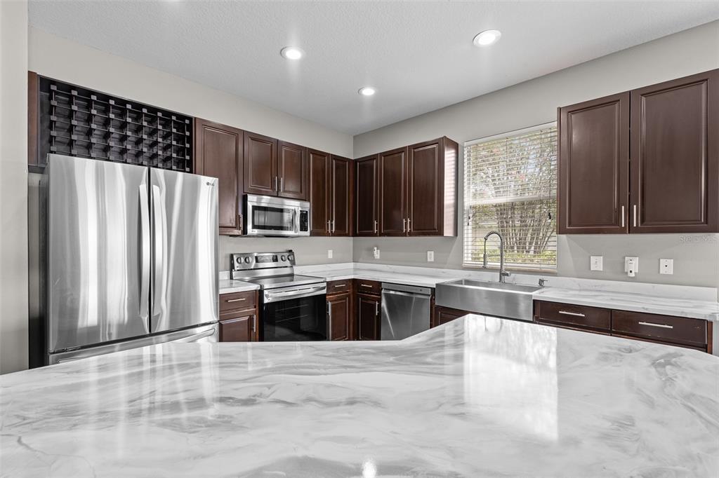 5909 Wedgefield Drive Zephyrhills, FL 33541 - Photo 12 of 54 a large kitchen with granite countertop a stove a sink a microwave a refrigerator and cabinets