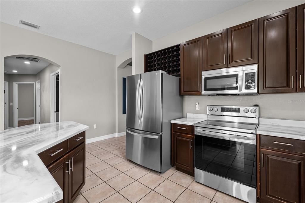 5909 Wedgefield Drive Zephyrhills, FL 33541 - Photo 14 of 54 a kitchen with granite countertop a stove microwave and refrigerator