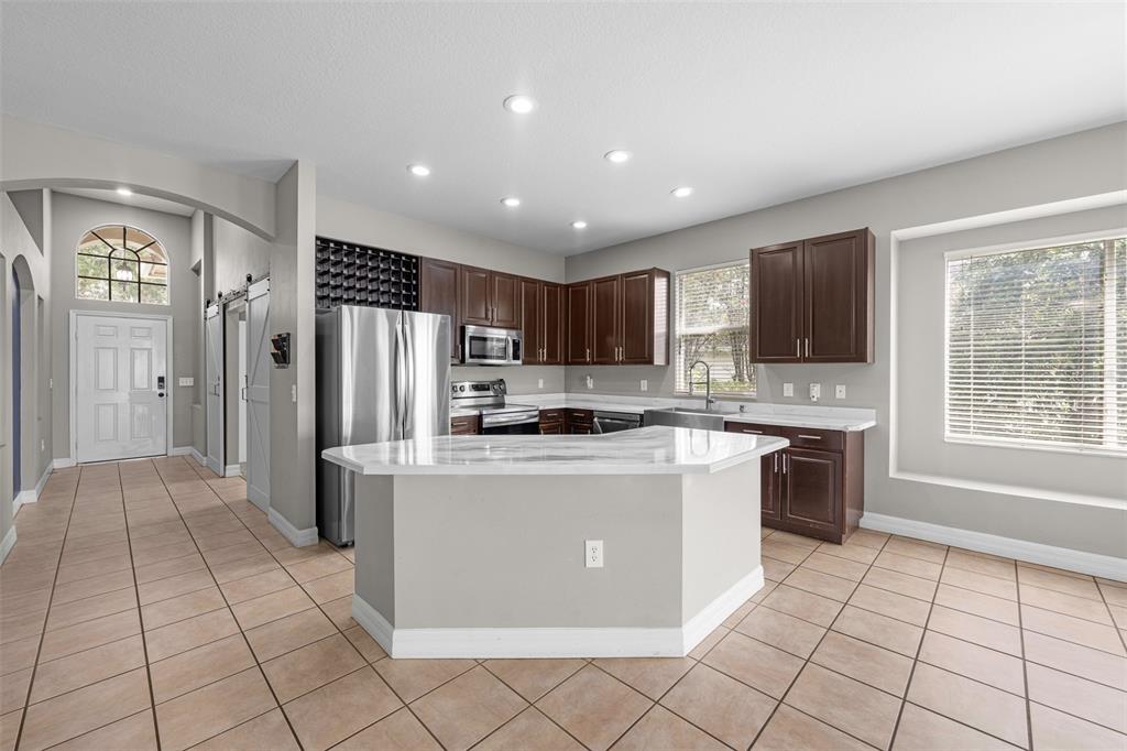 5909 Wedgefield Drive Zephyrhills, FL 33541 - Photo 15 of 54 a kitchen with stainless steel appliances granite countertop a refrigerator and a stove top oven