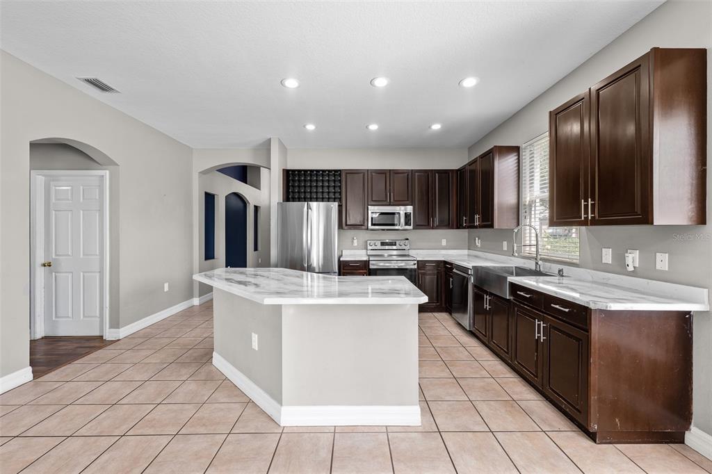 5909 Wedgefield Drive Zephyrhills, FL 33541 - Photo 16 of 54 a kitchen with stainless steel appliances granite countertop a stove top oven a sink and a refrigerator