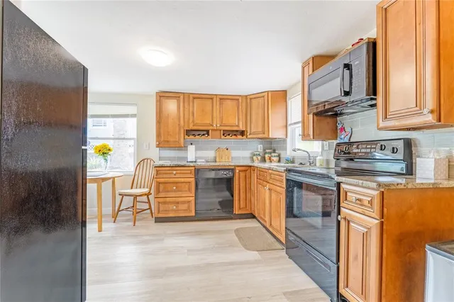 a kitchen with stainless steel appliances granite countertop a stove a sink and a refrigerator with wooden floors