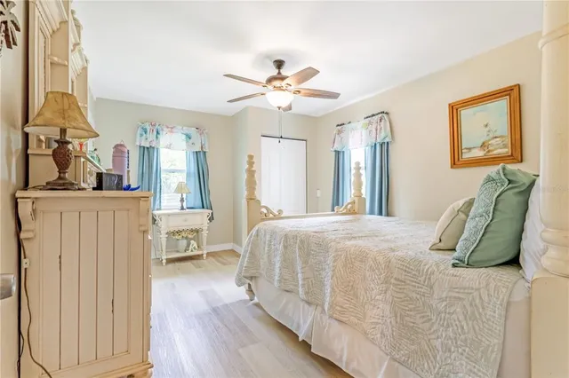a view of a bedroom with wooden floor and a ceiling fan