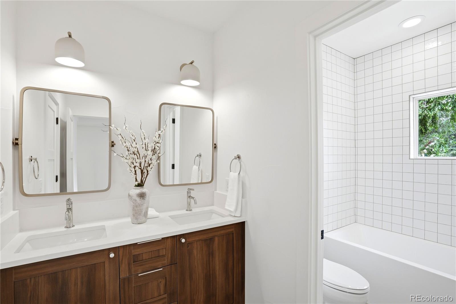 245 South Emerson Street Denver, CO 80209 - Photo 39 of 49 a bathroom with a double vanity sink and mirror with bathtub