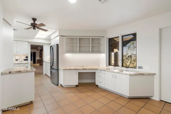 a view of an empty room with a large window and kitchen view