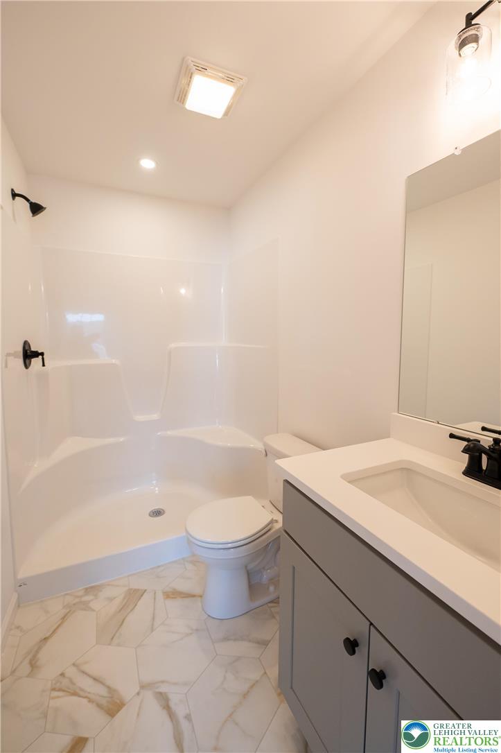 560 Long Street, Unit 1 Emmaus, PA 18049 - Photo 11 of 11 a bathroom with a granite countertop sink a toilet a mirror and bathtub