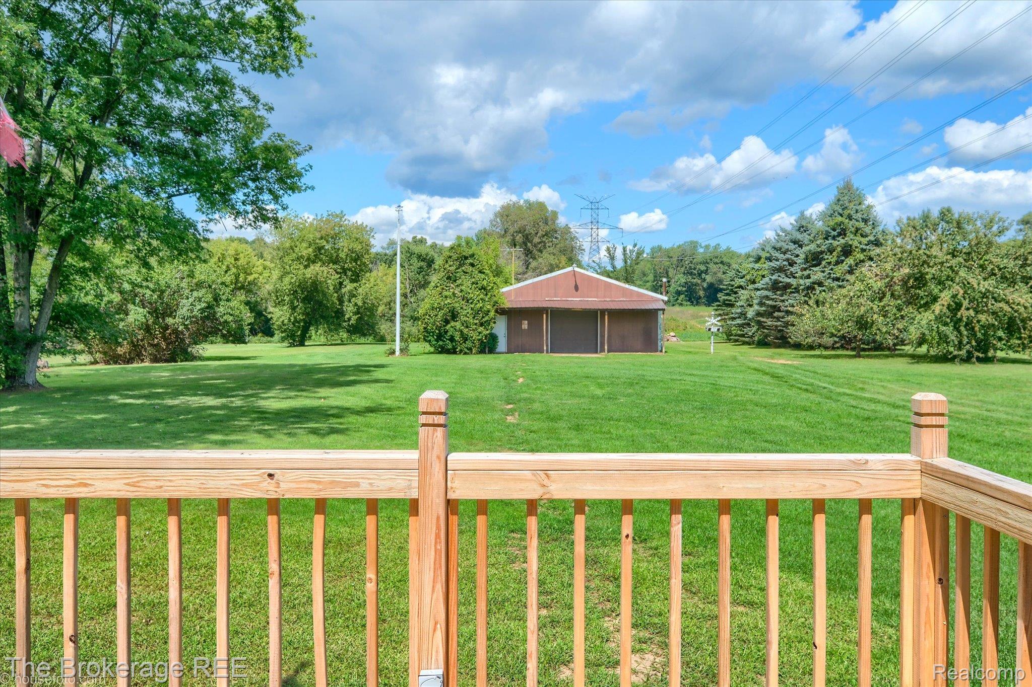 6129 East Lake Road Millington, MI 48746 - Photo 39 of 47 View of grassy yard featuring a detached garage, view of scattered trees, a balcony, an outdoor structure, and an outbuilding