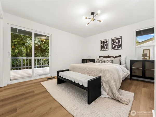 a spacious bedroom with a bed painting on wall and a large window