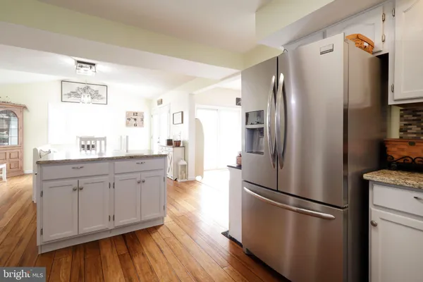 a kitchen with stainless steel appliances a stove a sink dishwasher a oven with white cabinets and wooden floor