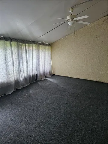 an empty room with a fan & a window