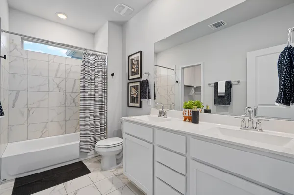 a bathroom with a double vanity sink toilet mirror and shower