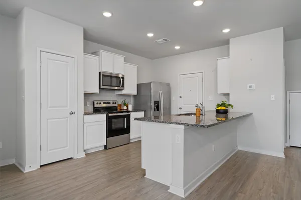 a kitchen with granite countertop white cabinets and stainless steel appliances