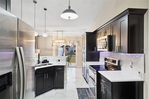 a kitchen with kitchen island a counter space a sink appliances and cabinets