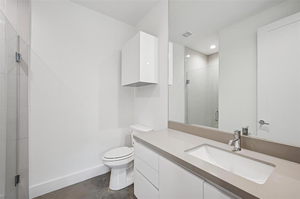 3064 ChImes Street Dallas, TX 75219 - Photo 30 of 40 a bathroom with a granite countertop sink a toilet and a mirror
