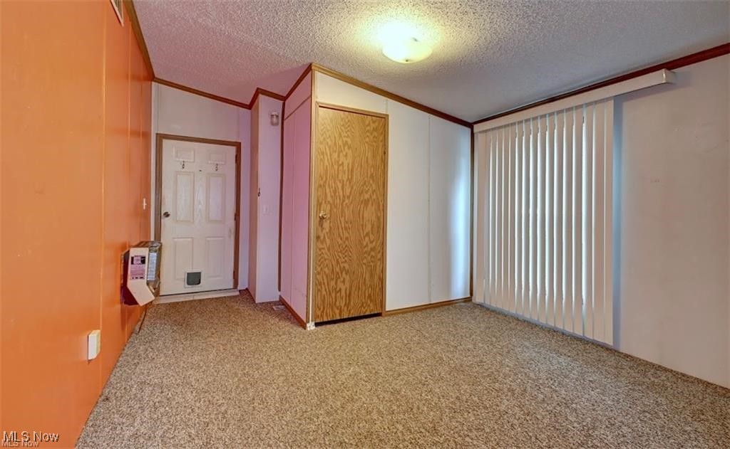6269 Columbia Road Northwest Dover, OH 44622 - Photo 7 of 8 Unfurnished bedroom featuring light colored carpet, crown molding, a textured ceiling, and a closet