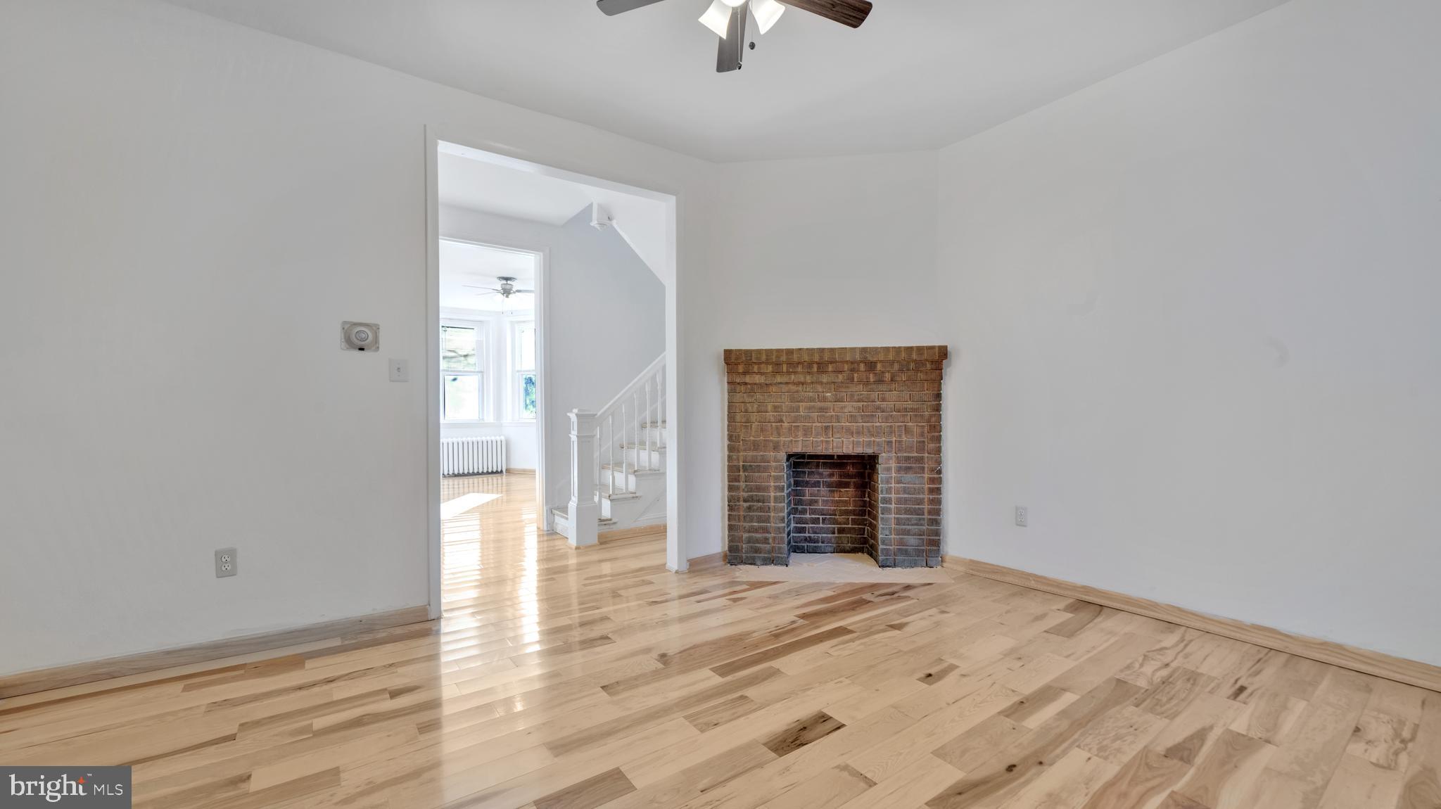 1528 E Street Southeast Washington, DC 20003 - Photo 6 of 19 an empty room with wooden floor fireplace and chandelier fan