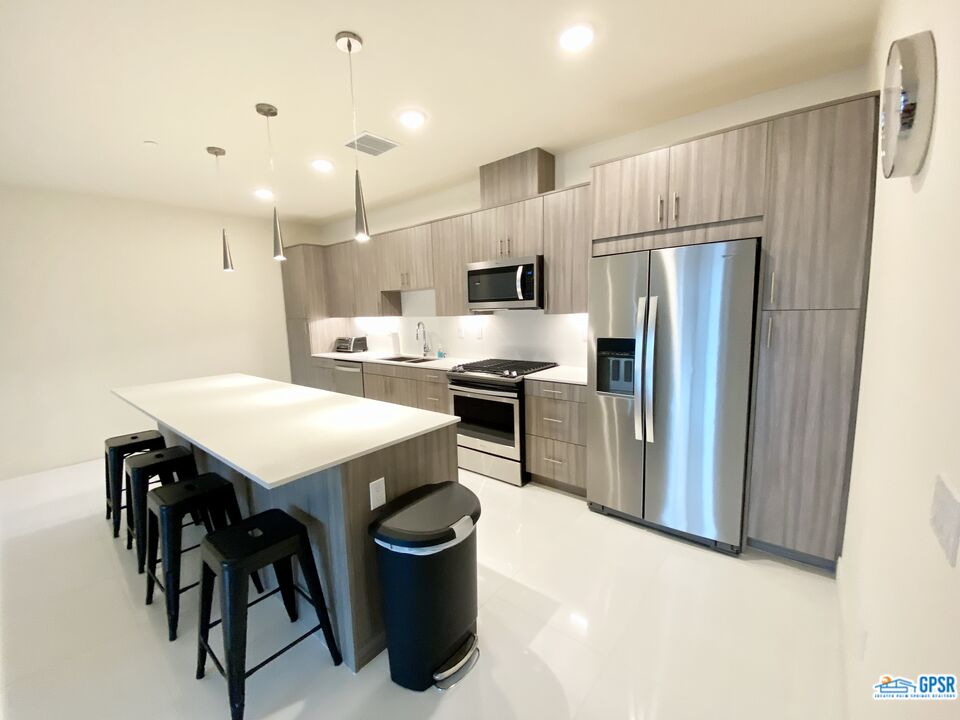 158 The River Palm Springs, CA 92262 - Photo 2 of 17 a kitchen with stainless steel appliances a refrigerator a sink a stove a dining table and chairs