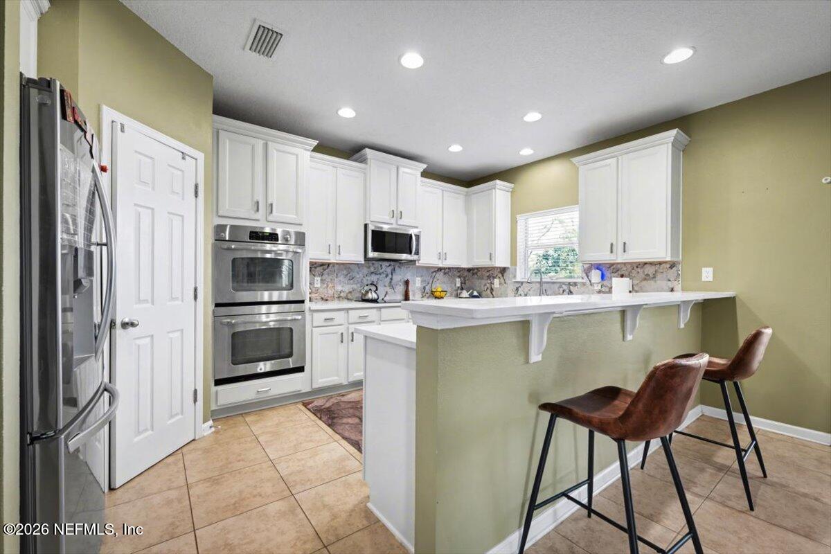 8131 Broward Cove Road Jacksonville, FL 32218 - Photo 21 of 35 a kitchen with kitchen island white cabinets appliances and chairs