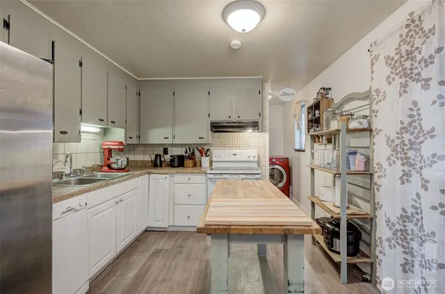 a kitchen with stainless steel appliances a stove a sink and white cabinets