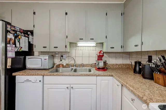 a kitchen with stainless steel appliances granite countertop a sink dishwasher and white cabinets