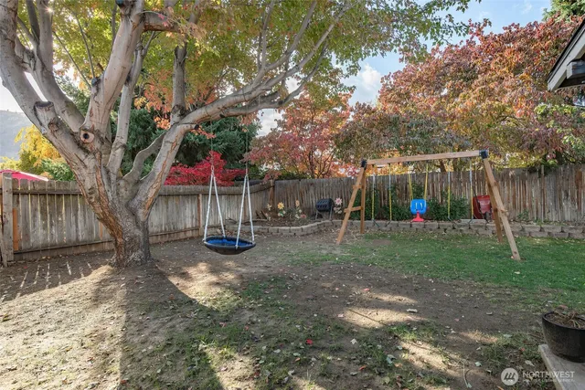 a view of backyard with wooden fence and a large tree
