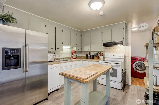 a kitchen with stainless steel appliances granite countertop a refrigerator a stove and a sink