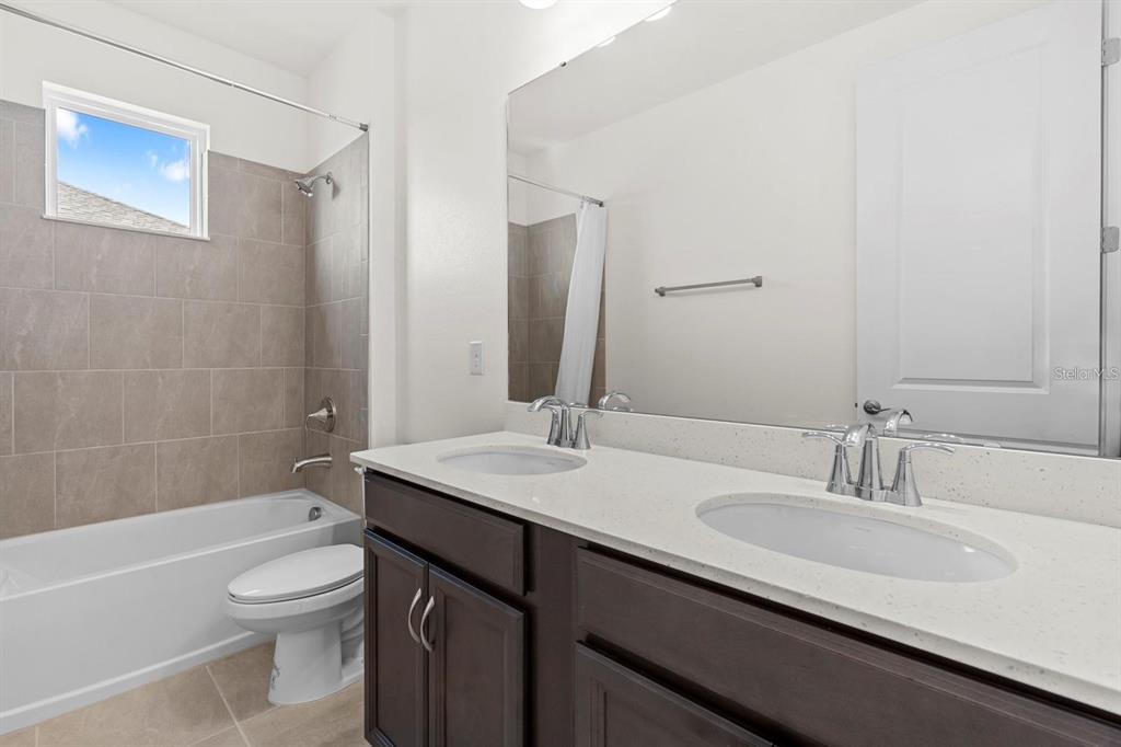 933 Signet Drive Apollo Beach, FL 33572 - Photo 43 of 66 a bathroom with a granite countertop sink toilet a large mirror a bathtub and shower