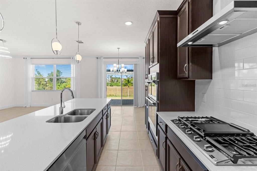 933 Signet Drive Apollo Beach, FL 33572 - Photo 7 of 66 a kitchen with stainless steel appliances granite countertop a sink a stove and a wooden floors