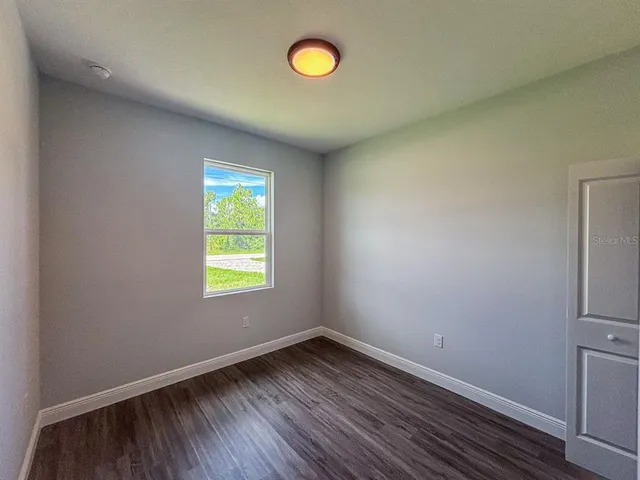 a view of empty room with window and wooden floor