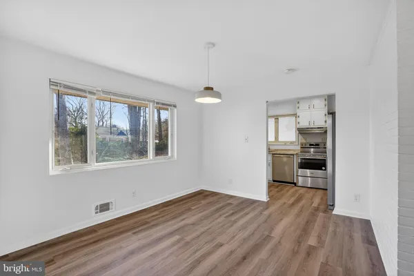 a view of a kitchen and an empty room with wooden floor kitchen view