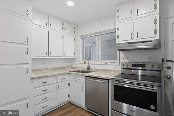 a kitchen with granite countertop white cabinets and white stainless steel appliances