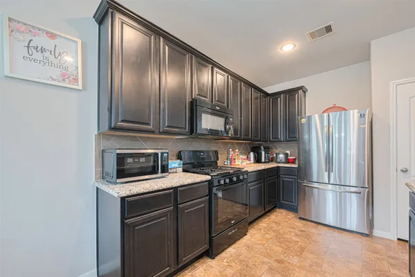 a kitchen with stainless steel appliances granite countertop a refrigerator sink and stove
