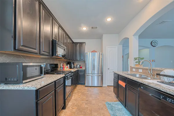 a kitchen with stainless steel appliances granite countertop a refrigerator a sink and wooden cabinets
