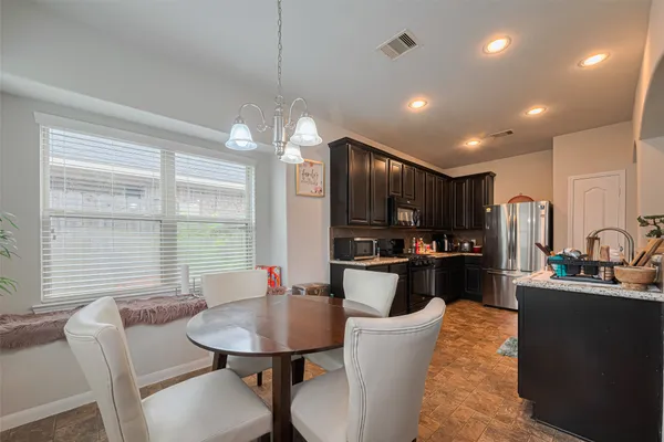 a kitchen with stainless steel appliances kitchen island granite countertop a dining table chairs refrigerator and sink